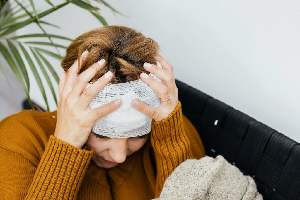 a woman holding her bandaged head